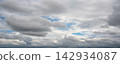 Panoramic view of dramatic gray storm clouds with patches of blue sky 142934087