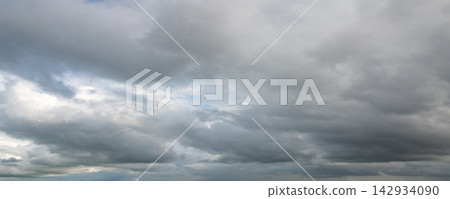 Panoramic view of dramatic gray storm clouds with patches of blue sky Panoramic view of dramatic gray storm clouds with patches of blue sky 142934090