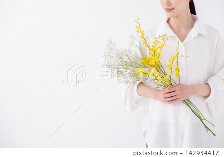 一位女子手捧一束花；文心蘭；特寫鏡頭拍攝她的雙手。 142934417