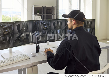 Modern Security Officer Watching CCTV Feeds in Surveillance Control Room Modern Security Officer Watching CCTV Feeds in Surveillance Control Room 142934673