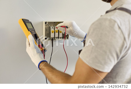 Close Up of Electrician Testing Circuit Breaker Panel With Multimeter Indoors Close Up of Electrician Testing Circuit Breaker Panel With Multimeter Indoors 142934732