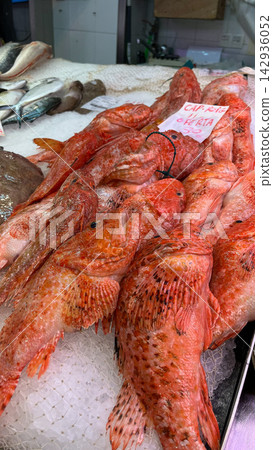 Fresh red fish displayed on ice at seafood market with price tag visible in background Fresh red fish displayed on ice at seafood market with price tag visible in background 142936052