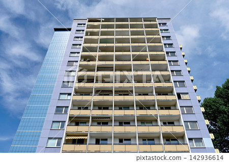 Low angle view looking up at a tall concrete apartment high rise building facade Low angle view looking up at a tall concrete apartment high rise building facade 142936614