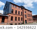 Historic red brick factory building with slate facade under blue sky 142936622