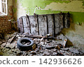 Abandoned building interior with broken tire debris and peeling green wall texture 142936626