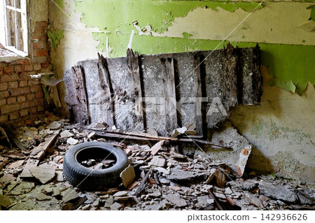 Abandoned building interior with broken tire debris and peeling green wall texture Abandoned building interior with broken tire debris and peeling green wall texture 142936626