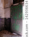 Weathered green wooden sliding door in an abandoned industrial room 142936634