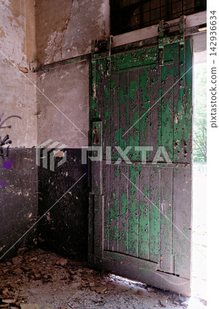 Weathered green wooden sliding door in an abandoned industrial room Weathered green wooden sliding door in an abandoned industrial room 142936634
