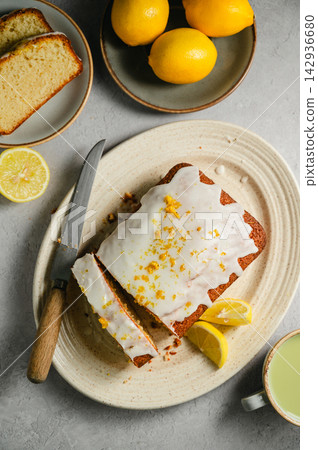Lemon loaf cake slices with lemon glaze, fresh lemons and matcha tea, lifestyle food Lemon loaf cake slices with lemon glaze, fresh lemons and matcha tea, lifestyle food 142936680