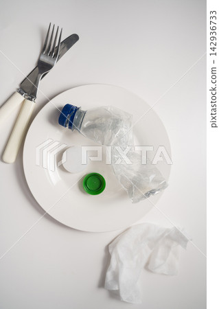 Plastic bottle served on plate with cutlery on white background, plastic pollution and waste concept Plastic bottle served on plate with cutlery on white background, plastic pollution and waste concept 142936733