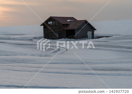 夕陽西下,雪原上矗立著一棟木屋。 夕陽西下,雪原上矗立著一棟木屋。 142937720