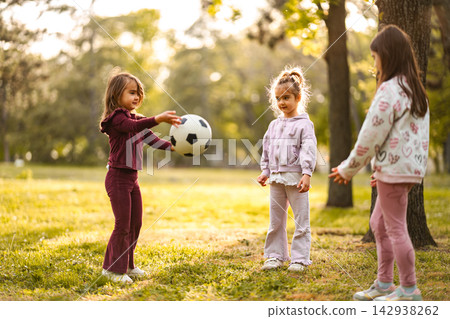 Little girls playing soccer in park at sunset Little girls playing soccer in park at sunset 142938262
