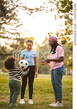 Family playing soccer outdoors, having fun in park 142938266