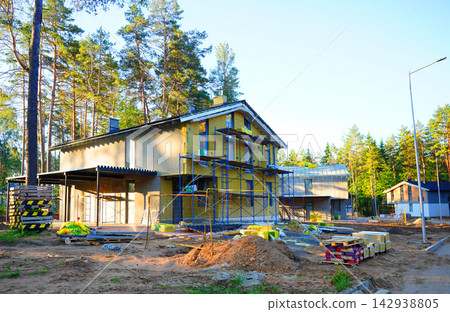 Suburb house under construction. Facade Insulation. Construction of a two-story cottage Suburb house under construction. Facade Insulation. Construction of a two-story cottage 142938805