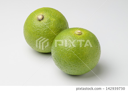 Two kabosu citrus fruits placed against a white background. Two kabosu citrus fruits placed against a white background. 142939730