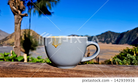 A close-up photo of a cup of coffee with Mount Bromo in the background. A close-up photo of a cup of coffee with Mount Bromo in the background. 142939916