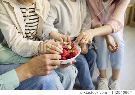 Family hands taking fresh strawberries from bowl at home, healthy snack time Family hands taking fresh strawberries from bowl at home, healthy snack time 142940904