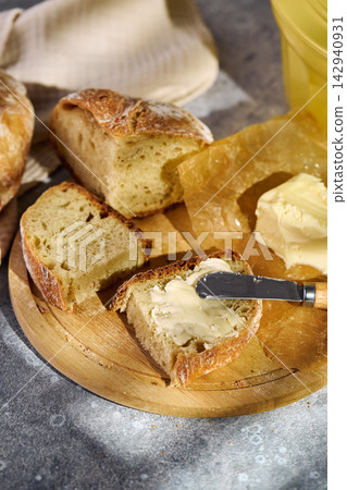 Spreading butter on fresh rustic sourdough bread slice Spreading butter on fresh rustic sourdough bread slice 142940931