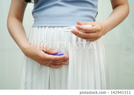 Asian holding pregnancy test for female of ovulation day, fetus, maternity, childbirth, birth control. Asian holding pregnancy test for female of ovulation day, fetus, maternity, childbirth, birth control. 142941311