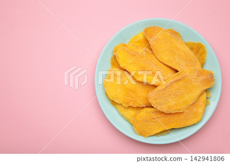Slices of dried mango on mint plate on pink background. Space for text Slices of dried mango on mint plate on pink background. Space for text 142941806