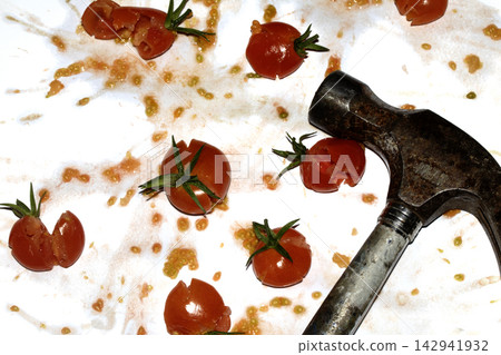 A squashed splattered and crushed broken fresh tomato with seeds being smashed by a hammer A squashed splattered and crushed broken fresh tomato with seeds being smashed by a hammer 142941932