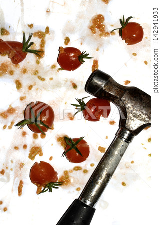 A squashed splattered and crushed broken fresh tomato with seeds being smashed by a hammer A squashed splattered and crushed broken fresh tomato with seeds being smashed by a hammer 142941933