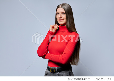 Confident woman in red turtleneck posing with hand on chin studio shot Confident woman in red turtleneck posing with hand on chin studio shot 142942055