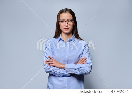 Young female student wearing eyeglasses and blue shirt on studio background 142942095