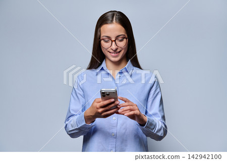 Young woman in glasses using smartphone smiling studio shot Young woman in glasses using smartphone smiling studio shot 142942100