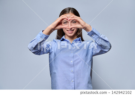 Young female student making heart sign with hands and smiling Young female student making heart sign with hands and smiling 142942102