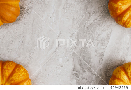 Fresh orange pumpkins set in four corners of light marble background creating central space for autumn promotional banner or seasonal festival announcement Fresh orange pumpkins set in four corners of light marble background creating central space for autumn promotional banner or seasonal festival announcement 142942389