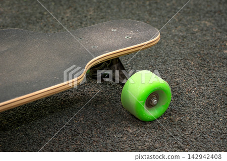 Old used skateboard isolated on the ground. Old style longboard. Black skateboard on an empty asphalt road. Shallow depth of field. Old used skateboard isolated on the ground. Old style longboard. Black skateboard on an empty asphalt road. Shallow depth of field. 142942408