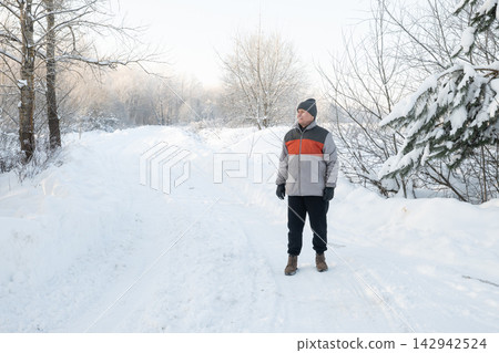 Mature man walking alone on snowy winter road Mature man walking alone on snowy winter road 142942524
