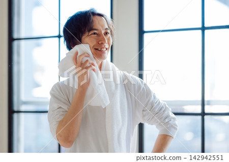 A man in an apron wiping sweat with a towel. 142942551