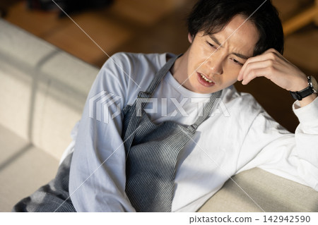 A man in an apron resting on a sofa. A man in an apron resting on a sofa. 142942590