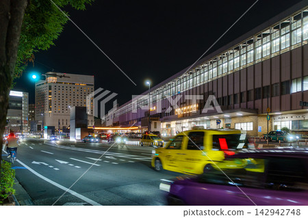 夜幕降臨,計程車和城市交通工具從車站前駛過。 夜幕降臨,計程車和城市交通工具從車站前駛過。 142942748