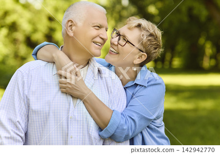 Happy senior couple hugging in sunny park, smiling with love and joy outdoors 142942770