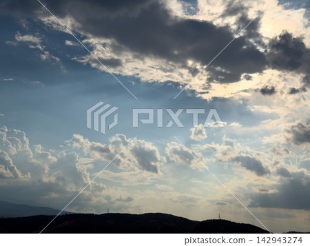 Dramatic backlit clouds glowing above dark rolling hills Dramatic backlit clouds glowing above dark rolling hills 142943274