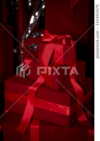 Festive red gift boxes tied with satin ribbons for holiday celebrations Festive red gift boxes tied with satin ribbons for holiday celebrations 142943879