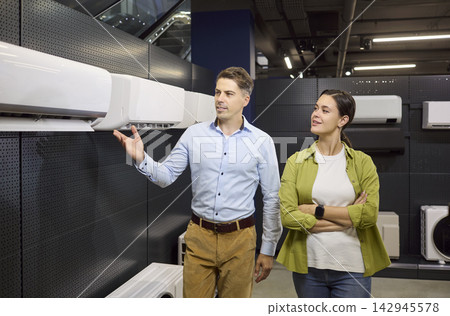 Smiling couple choosing air conditioner in retail appliance store interior Smiling couple choosing air conditioner in retail appliance store interior 142945578