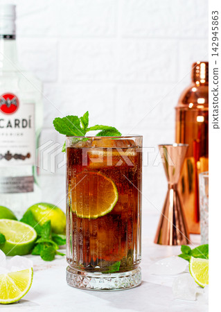 Making a Cuba libre cocktail, with Bacardi rum, limes, mint and ice, harsh light, no people. Making a Cuba libre cocktail, with Bacardi rum, limes, mint and ice, harsh light, no people. 142945863