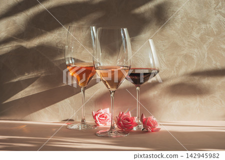 Three glasses of different wines with roses and textured background artistic composition 142945982