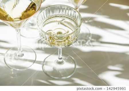 Elegant crystal coupe and martini glasses filled with golden champagne or wine Elegant crystal coupe and martini glasses filled with golden champagne or wine 142945991