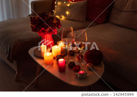 Cozy autumn evening setup with wine glasses candles pumpkins and seasonal decor on a table near a sofa with fairy lights Cozy autumn evening setup with wine glasses candles pumpkins and seasonal decor on a table near a sofa with fairy lights 142945994