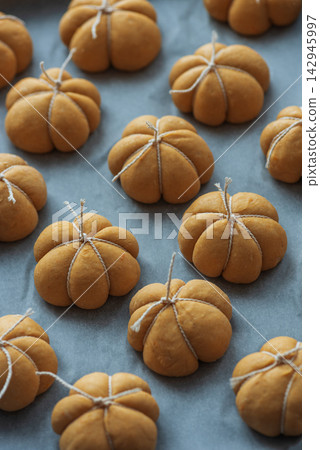 Collection of small decorative pumpkin shaped baked goods tied with twine on baking paper Collection of small decorative pumpkin shaped baked goods tied with twine on baking paper 142945997