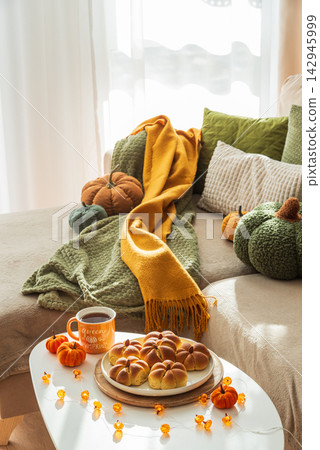 Cozy Autumn Scene with Pumpkin Buns and Hot Drink on Coffee Table Cozy Autumn Scene with Pumpkin Buns and Hot Drink on Coffee Table 142945999