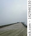 Long Wooden Fishing Pier Extending into Dense Coastal Fog 142946330
