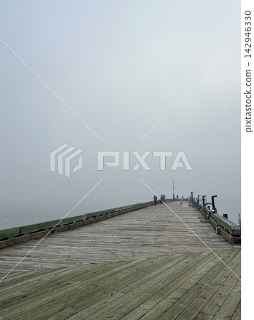 Long Wooden Fishing Pier Extending into Dense Coastal Fog Long Wooden Fishing Pier Extending into Dense Coastal Fog 142946330