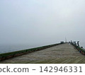 Long Wooden Fishing Pier Extending into Dense Coastal Fog 142946331
