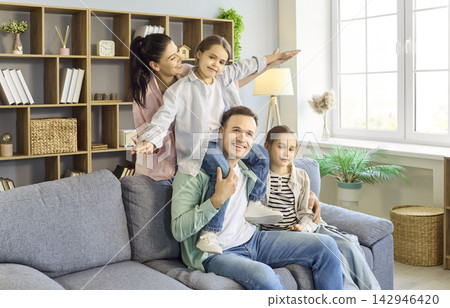 Happy parents with two children hugging and playing on sofa at cozy home interior Happy parents with two children hugging and playing on sofa at cozy home interior 142946420